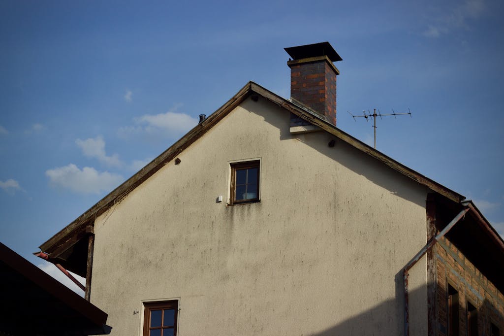 A rustic house exterior with a brick chimney set against a clear blue sky.